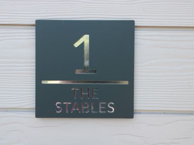 A sign displaying number 1 and the text THE STABLES at 1 The Stables Highbridge