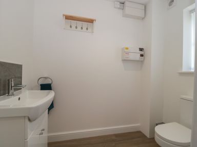 A bathroom with a sink, toilet, towel rack and electrical box at 1 The Stables Highbridge