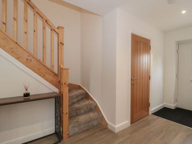 A hallway with a staircase and console table at 1 The Stables in Highbridge