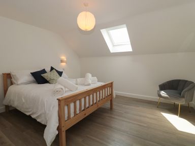 A bedroom with a bed and a chair at 1 The Stables in Highbridge