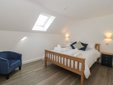 A bedroom with a bed and chair at 1 The Stables in Highbridge