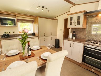 A kitchen with a dining area and modern appliances at 22 Yealand in Carnforth