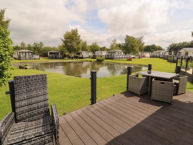 An outdoor area with a table and chairs overlooking a pond at 22 Yealand in Carnforth