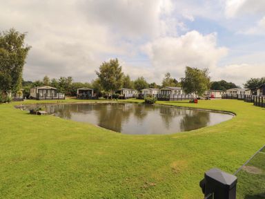 An outdoor area with a pond and mobile homes at 22 Yealand in Carnforth