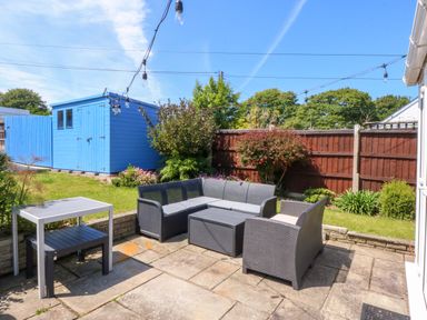 A garden with seating area and a blue shed at Swn Y Don