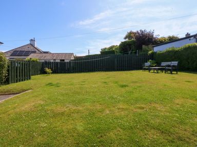 A garden with grass and a wooden bench at Swn Y Don