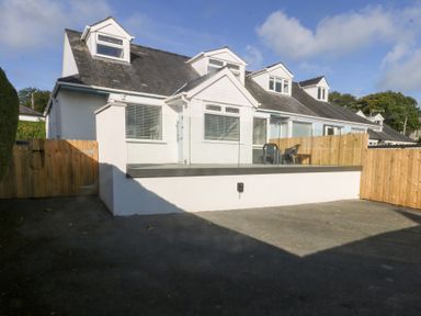A house with a deck and chairs at Swn Y Don in Llanbedrog