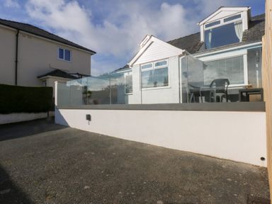 An outdoor area with a glass railing and seating at Swn Y Don in Llanbedrog