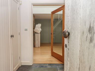 An entrance hall with a sculpture and mirror at Lower Velwell Barn in Totnes