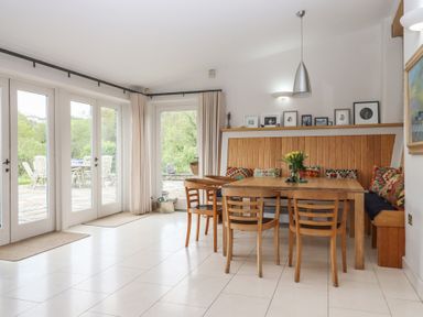 A dining room with a wooden table and chairs at Lower Velwell Barn in Totnes