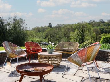 An outdoor seating area with chairs and a table at Lower Velwell Barn in Totnes