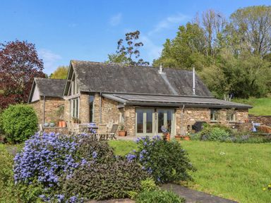 A house with outdoor seating and flowers at Lower Velwell Barn Totnes