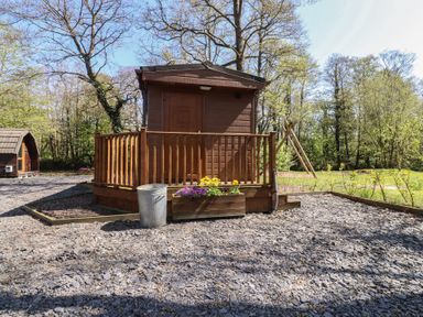A cabin with a deck and planter in a woodland area at Butterfly Hut 2 Forton near Garstang