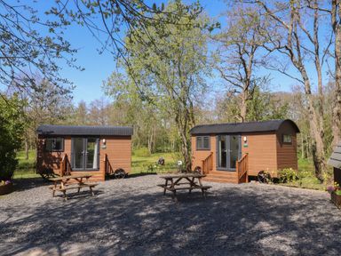 Two cabins with a picnic table in an outdoor area at Butterfly Hut 2 in Forton near Garstang