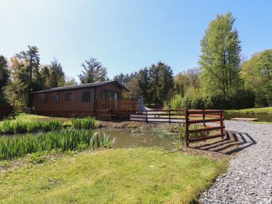A cabin with a deck near a pond at Butterfly Hut 2 Forton near Garstang