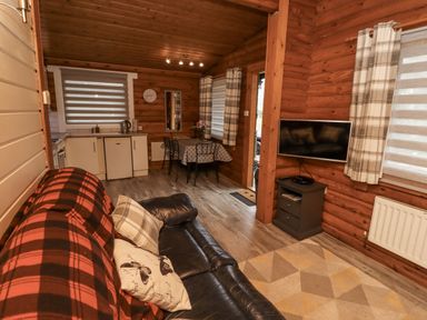 A living room with a sofa and kitchen in Farnes Lodge Longframlington