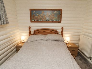 A bedroom with a bed, nightstand, lamp, and radiator at Farnes Lodge in Longframlington
