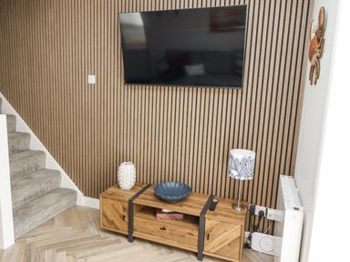 A living room with a television and wooden furniture at Seahorse Cottage in Chathill