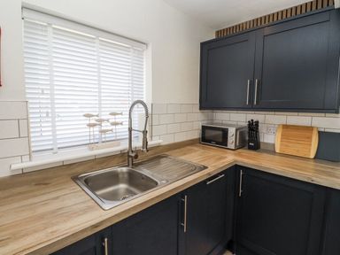 A kitchen with a sink and microwave at Seahorse Cottage in Chathill