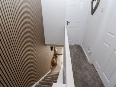 A hallway with stairs and a mirror at Seahorse Cottage in Chathill