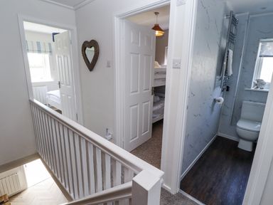 A hallway with a staircase and doors to rooms at Seahorse Cottage in Chathill