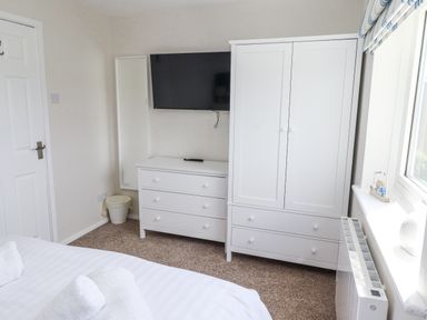 A bedroom with a television and wardrobe at Seahorse Cottage in Chathill