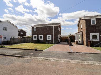 A view of two houses and a lawn at Seahorse Cottage in Chathill