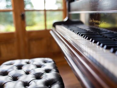 A piano and bench in a music room at Grove House in Grange-Over-Sands