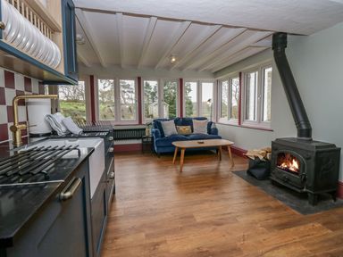 A kitchen with a stove and a couch at Grove House in Grange-Over-Sands