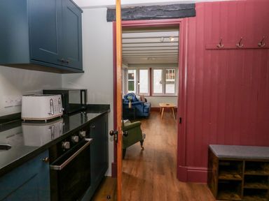 A kitchen with various appliances and an opening to a living area at Grove House in Grange-Over-Sands
