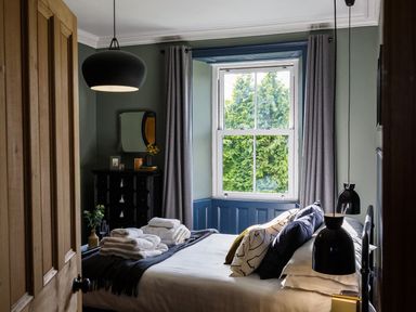 A bedroom with a bed, dresser, and window at Grove House in Grange-Over-Sands