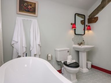 A bathroom with a bathtub, toilet, and sink at Grove House in Grange-Over-Sands