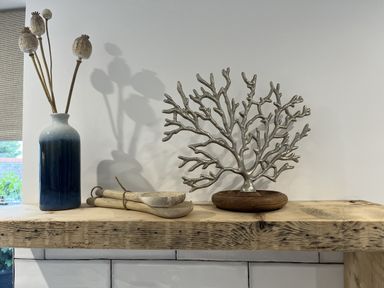 A decorative arrangement including a vase with flowers and a coral piece on a wooden shelf at 21 Station Hill