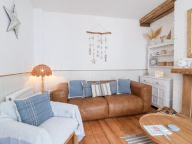 A living room with a sofa and shelves at Still Waters in Brixham