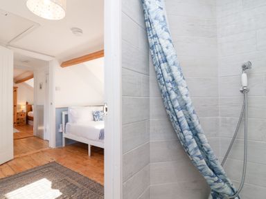 A bathroom with a shower curtain and wooden floor at Still Waters in Brixham