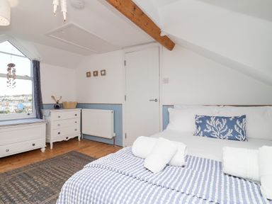A bedroom with a bed, dresser, and window at Still Waters in Brixham