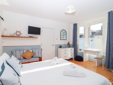 A bedroom with a bed, sofa, television, and desk at Still Waters in Brixham