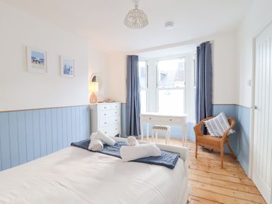 A bedroom with a bed, desk, and chair at Still Waters in Brixham