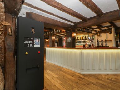 A bar with a photo booth and wooden beams at Penny Farthing Inn Aston Crews near Ross-On-Wye