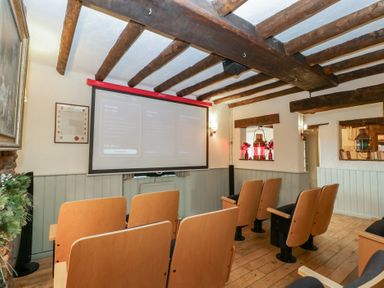 A cinema room with chairs facing a projector screen at Penny Farthing Inn Aston Crews near Ross-On-Wye