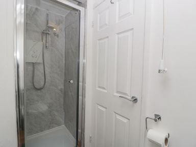 A shower with a door and towel holder at Penny Farthing Inn Aston Crews near Ross-On-Wye