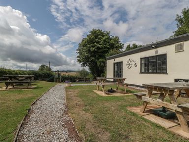 An outdoor area with picnic tables and playground equipment at Penny Farthing Inn Aston Crews near Ross-On-Wye