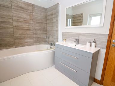 A bathroom with a bathtub and sink at Byron’s Retreat in Crantock