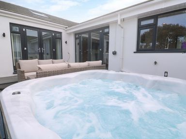 A hot tub and outdoor seating area at Byron’s Retreat Crantock
