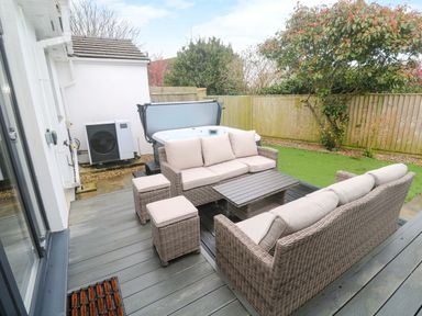 An outdoor area with a hot tub and seating at Byron’s Retreat in Crantock