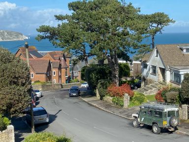 A street view with houses and vehicles near the sea at Purbeck Vista, Swanage