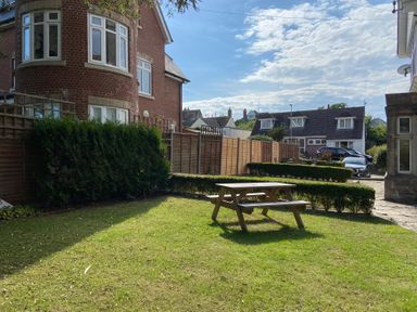 A garden with a picnic table and hedges at Purbeck Vista in Swanage
