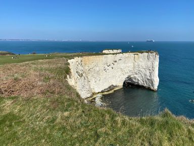 A cliff overlooking the ocean with people in the background at Purbeck Vista in Swanage