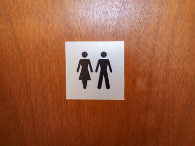 A sign with male and female symbols on a wooden door at Hayloft in Ipswich