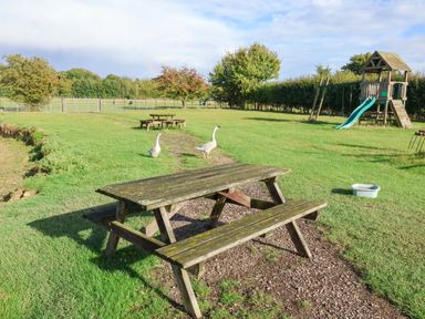 An outdoor area with a picnic table and playground at Hayloft in Ipswich